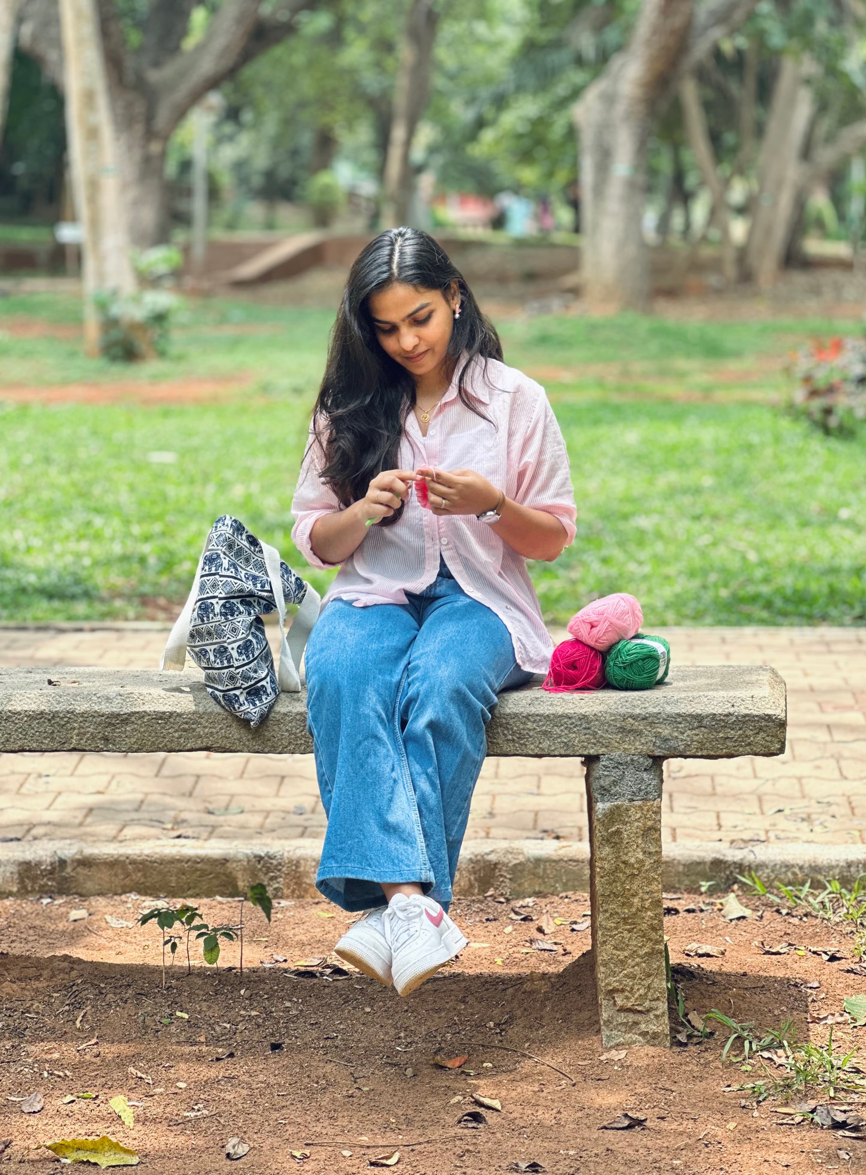 Dinashree crocheting on a park bench