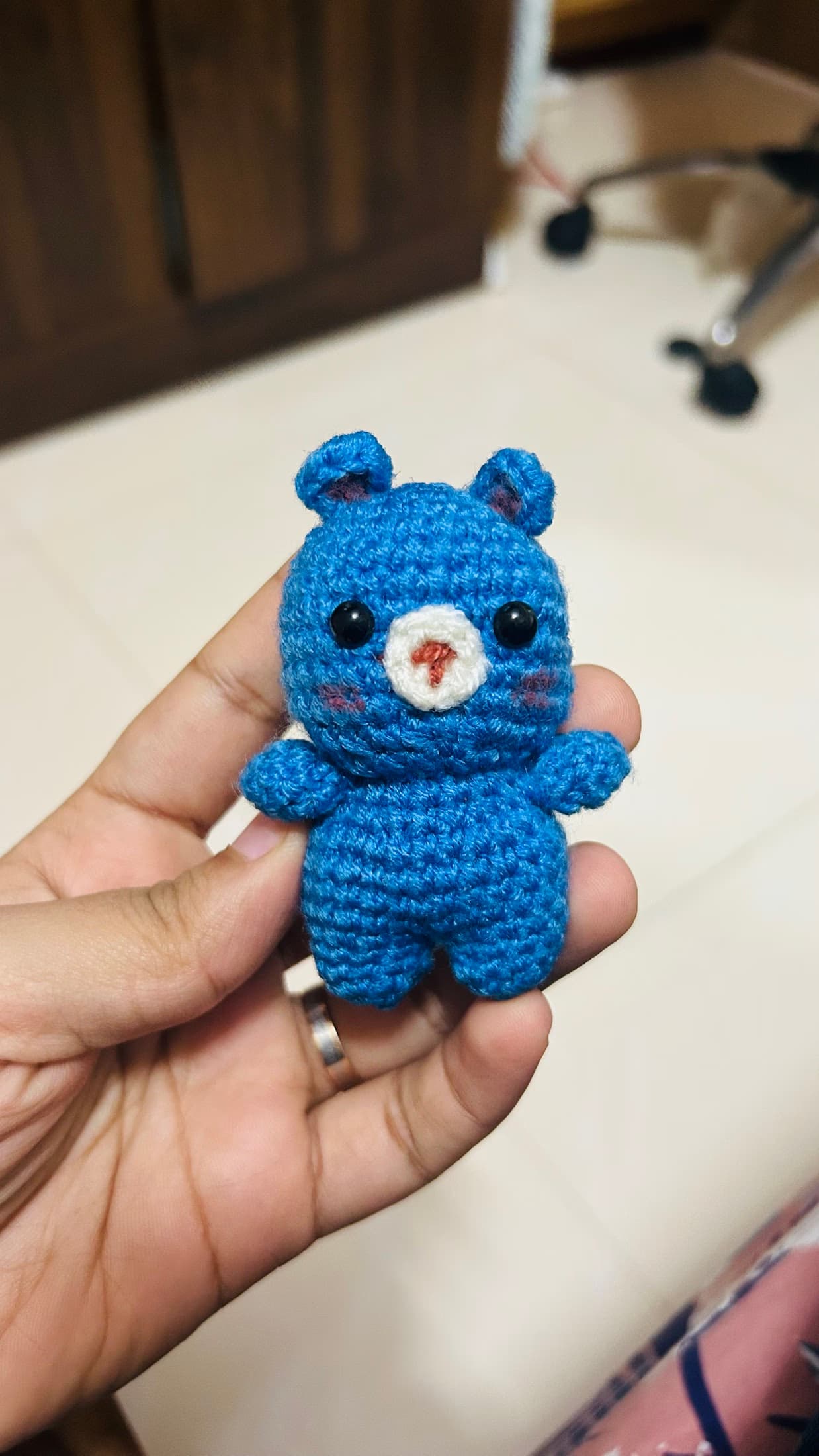 Blue crochet bear held in one hand