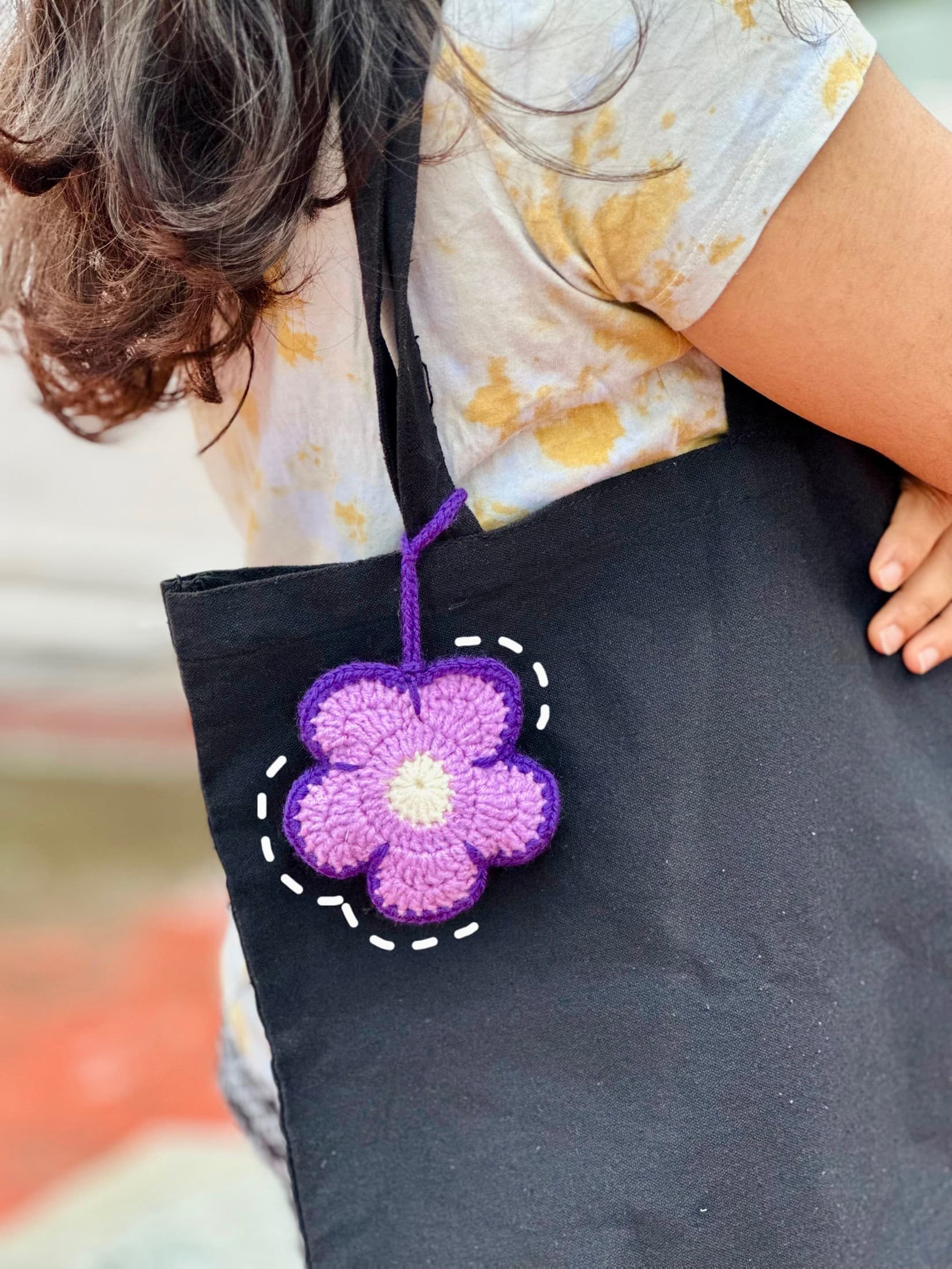 Purple crochet flower charm on a black tote bag