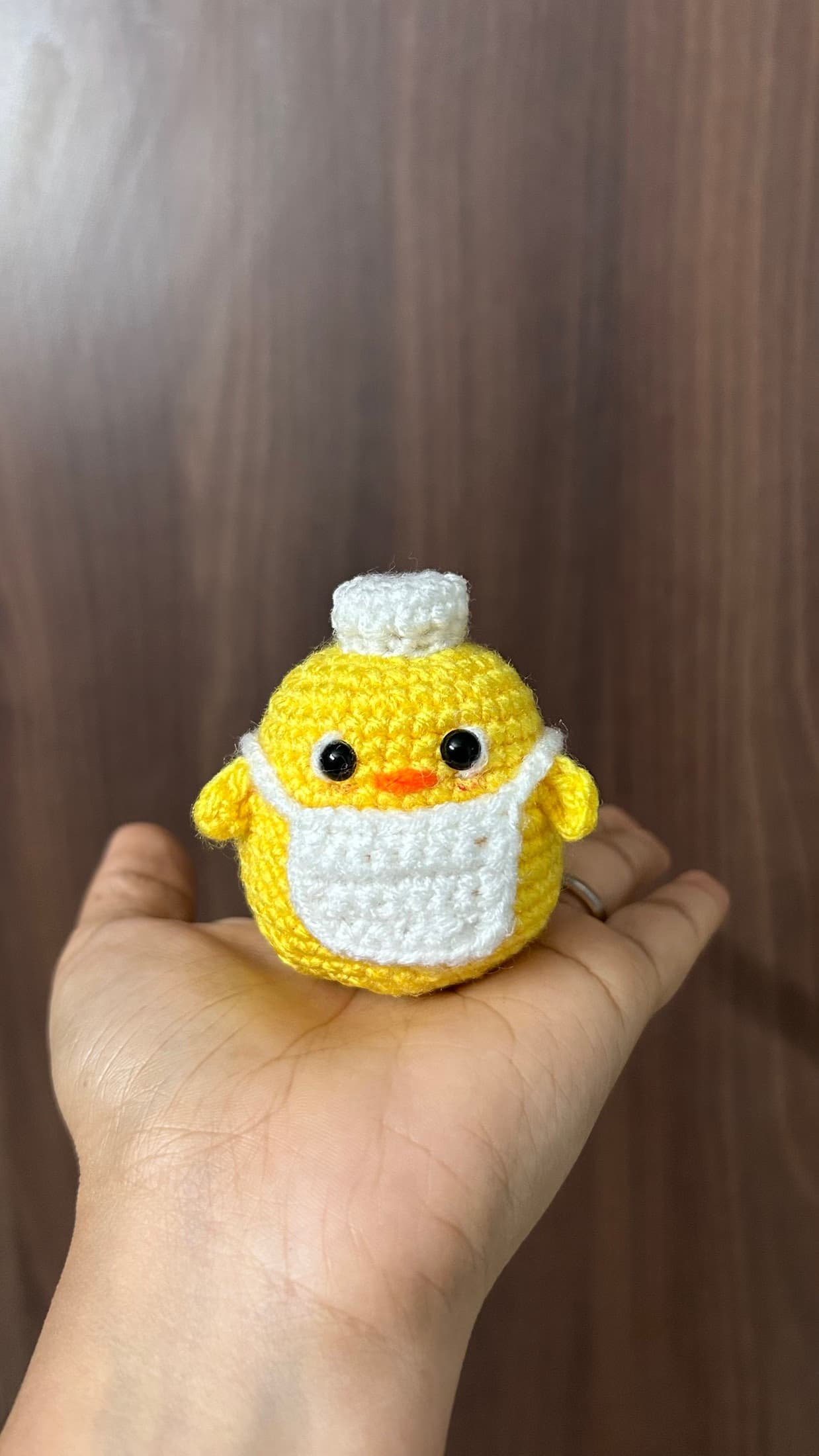 Yellow crochet duck held in one hand