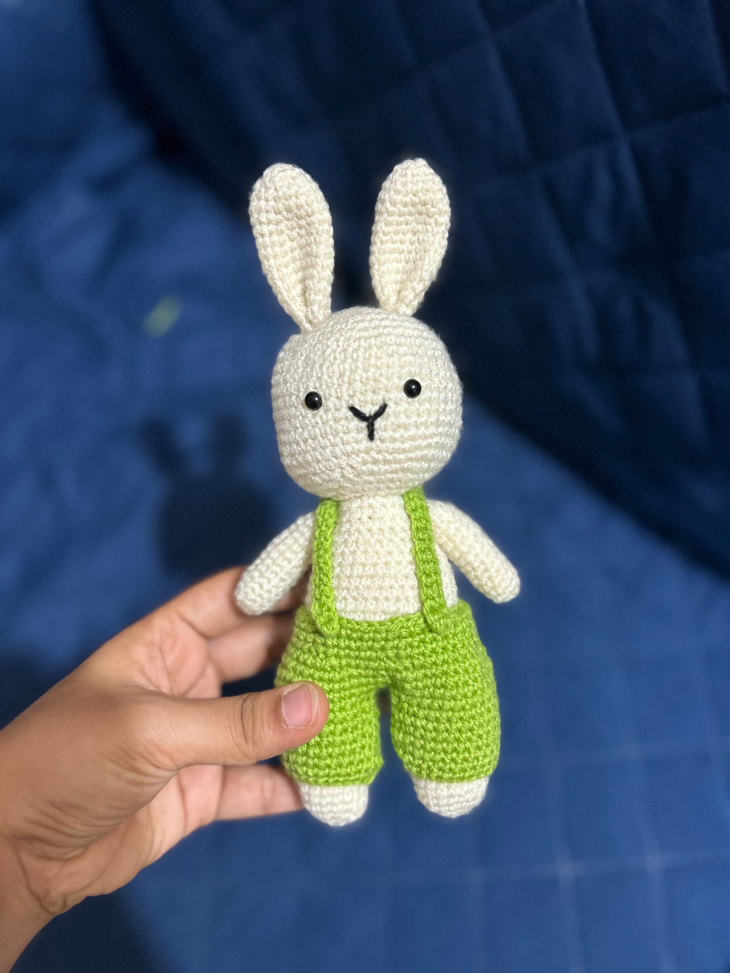 Crochet bunny wearing green overalls