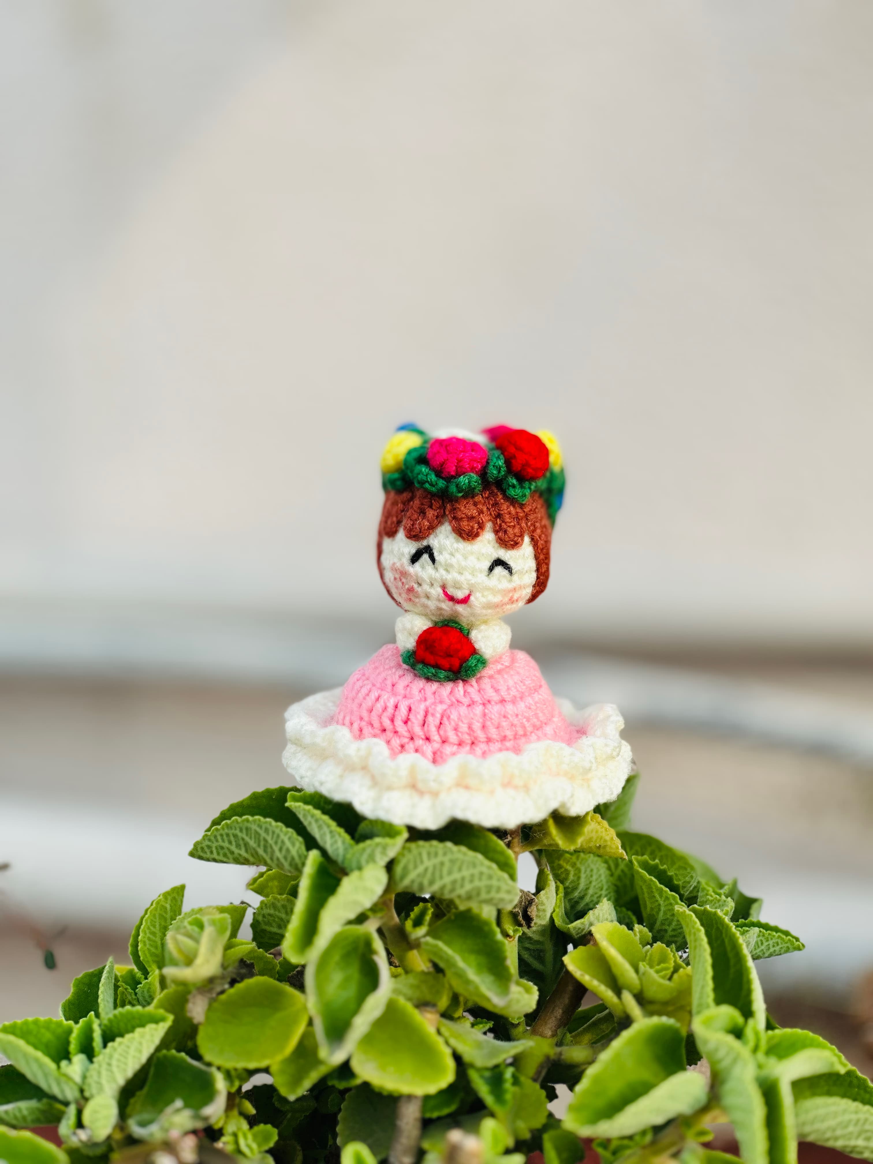 Crochet flower doll placed on a plant